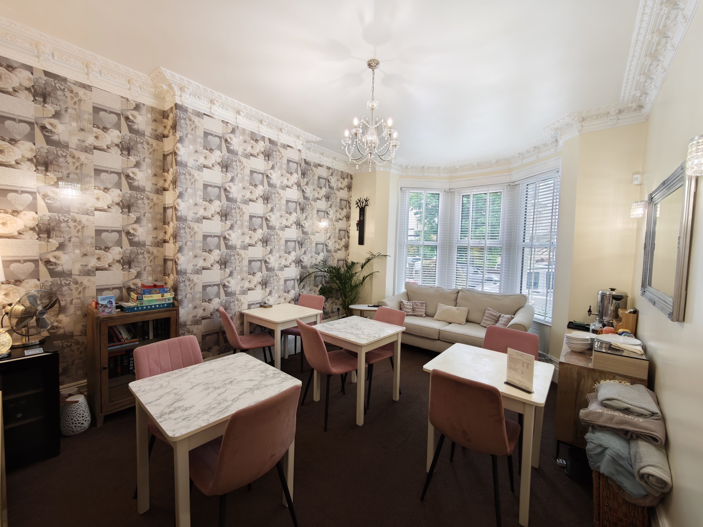 The all-day guest lounge at The Rosedene, Llandudno — tables, sofa, books and board games, yours to use from morning to night